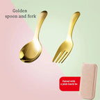 Gold spoon and fork set on a pink and green gradient background with a pink pouch.