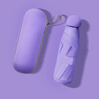 A compact purple folding umbrella and its matching hard-shell carrying case, shown on a solid lavender background.