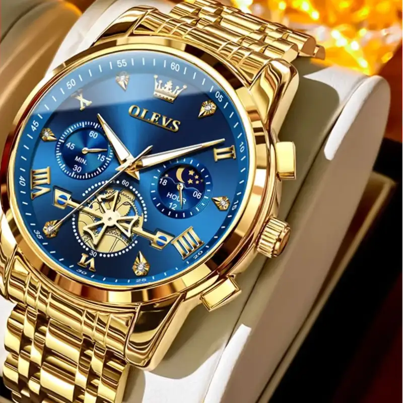 Gold watch with blue face on a white strap, branded OLEVS, on a dark background.