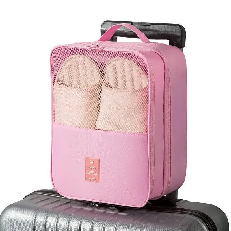 Pink travel packing cube on a suitcase with a white background