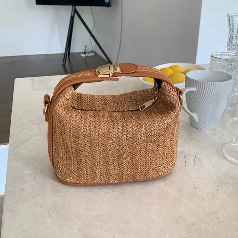 Brown woven handbag on a light-colored surface with a blurred background