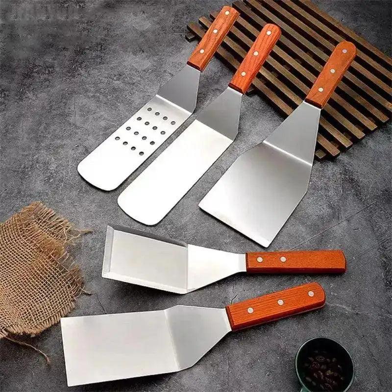 Set of metal spatulas with wooden handles on a gray surface