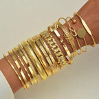 Gold bracelets on a wrist against a neutral background
