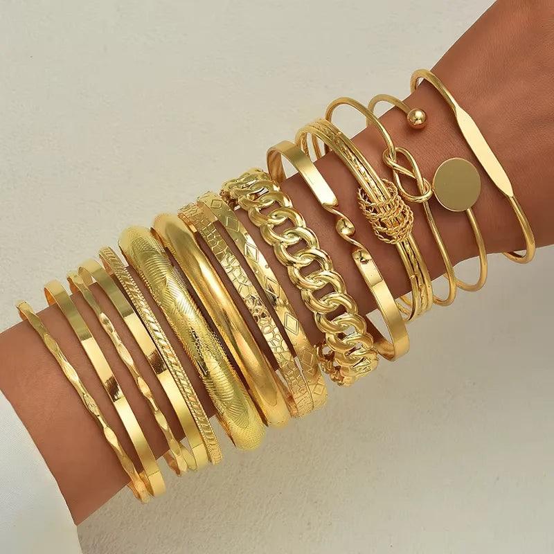 Gold bracelets on a wrist against a neutral background