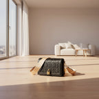 Black handbag with beige strap on a light gray background