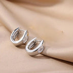 Pair of silver hoop earrings on a beige fabric background