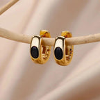 Gold hoop earrings with black stones on a beige background