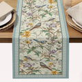 Decorative table runner with floral and bird pattern on a wooden table.