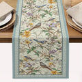 Decorative table runner with floral and bird pattern on a wooden table.
