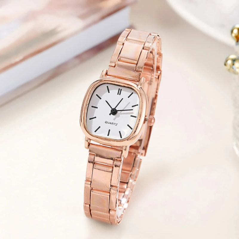 Rose gold watch with a white face on a light background