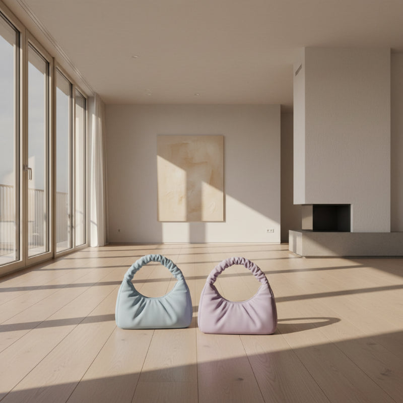 Two pastel-colored handbags on a black tray with a neutral background