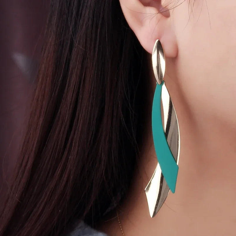 Close-up of a person wearing a silver and teal earring.