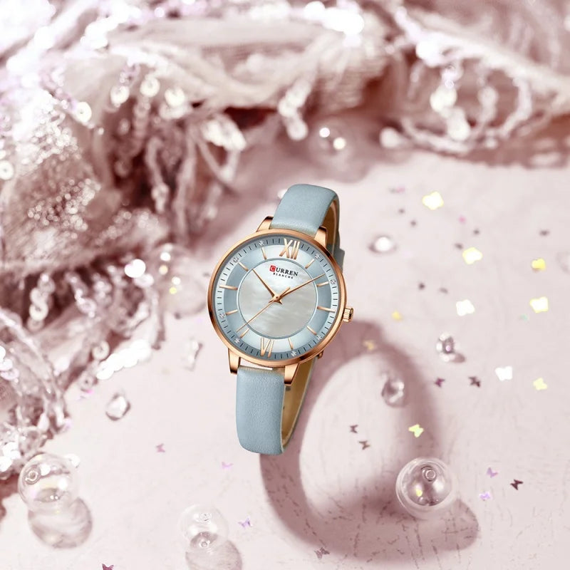 Watch with light blue strap and gold casing on a decorative background