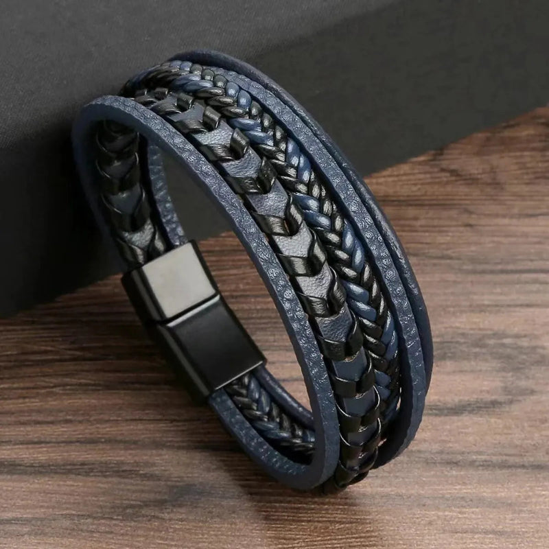 Black braided leather bracelet with a metal clasp on a wooden surface