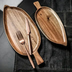 Wooden serving platters with a knife and fork on a dark surface