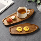 Wooden trays with a cup of tea, strawberries, and yellow pastries on a gray surface.