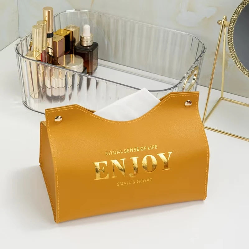 Yellow pouch with 'ENJOY' text next to a clear container with cosmetic items on a white surface.