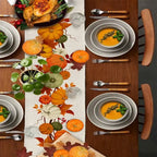 Thanksgiving table setting with a colorful table runner, plates, and utensils.
