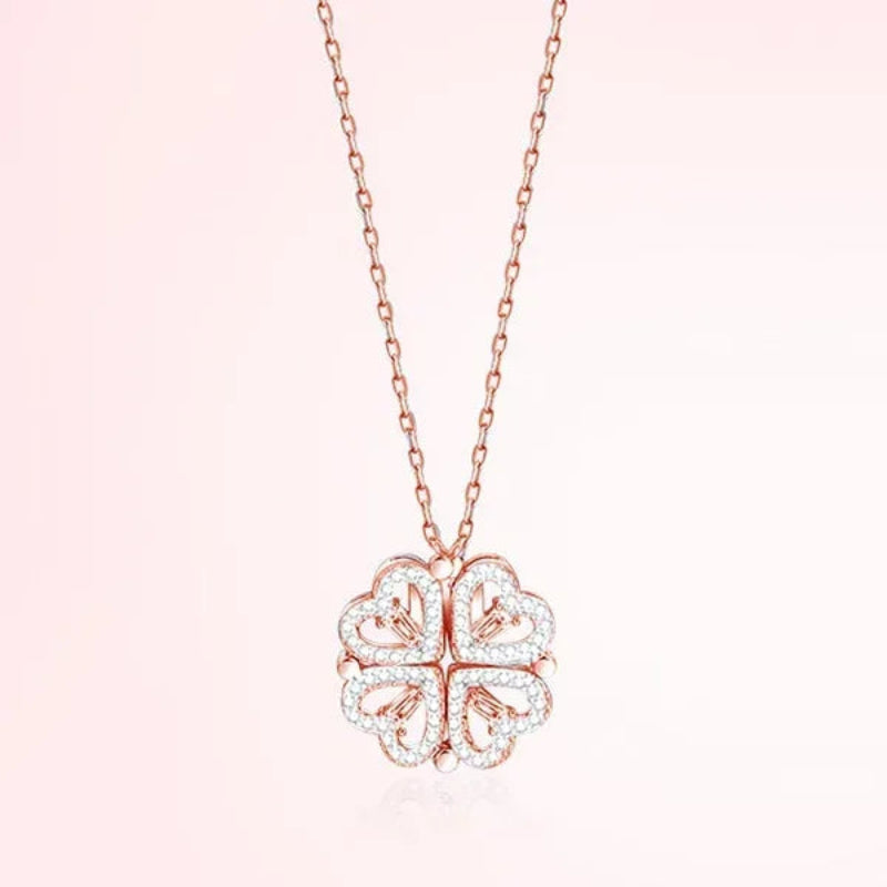 Rose gold four-leaf clover pendant necklace on a light pink background