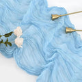 Light blue fabric with gold candle holders and white flowers on a white background