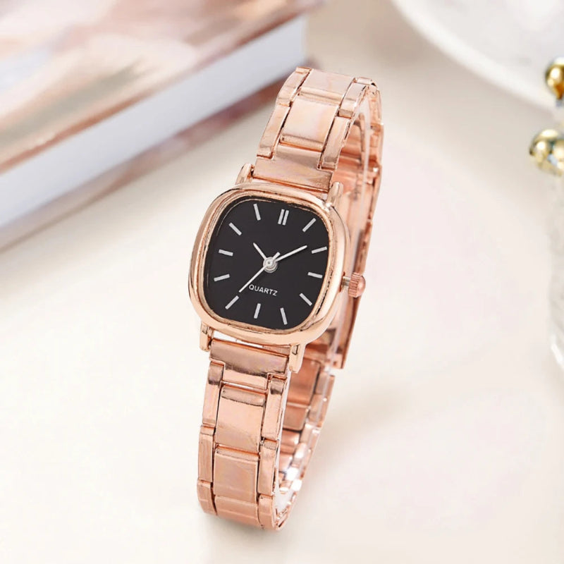 Rose gold watch with black dial on a light background