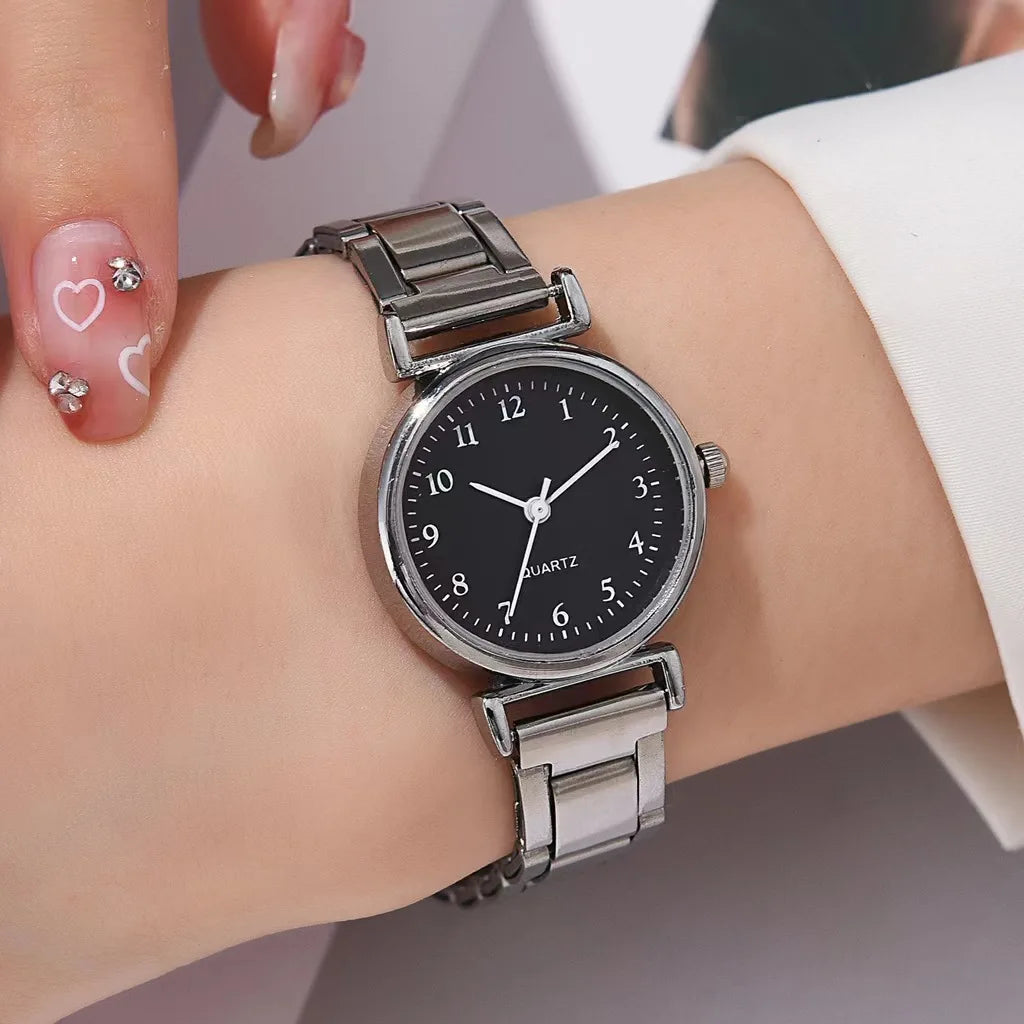 Silver watch on a wrist with a black dial