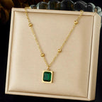 Gold necklace with a green gemstone pendant on a beige display box.