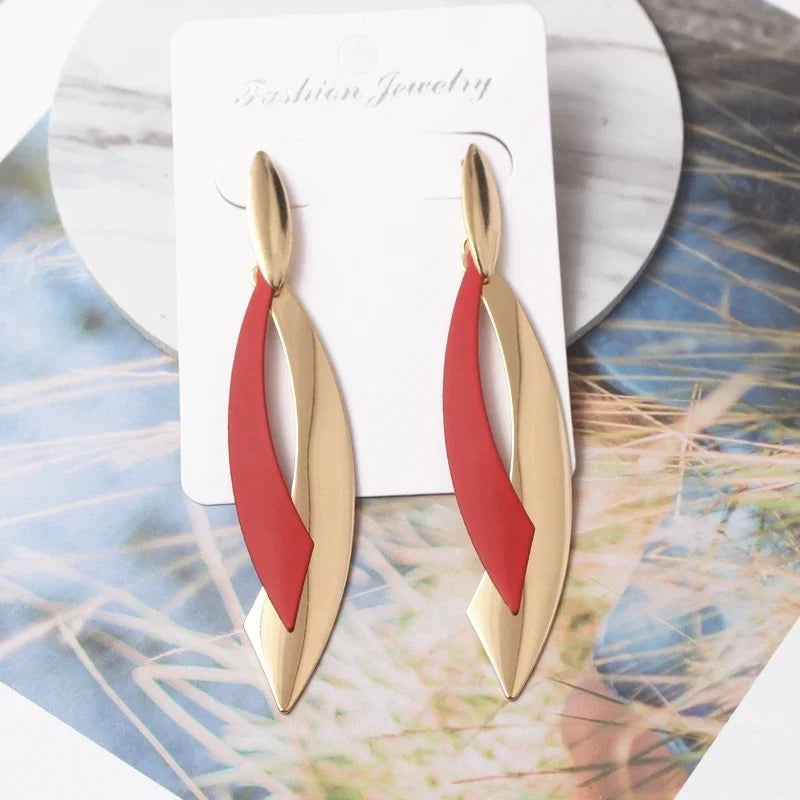 Gold and red earrings on a jewelry card with a natural background