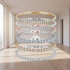 Five Andara tennis bracelets stacked vertically on a white background, featuring gold, silver, and rose gold metal settings with clear pavé stones. The Andara brand logo is visible in the top left corner.
