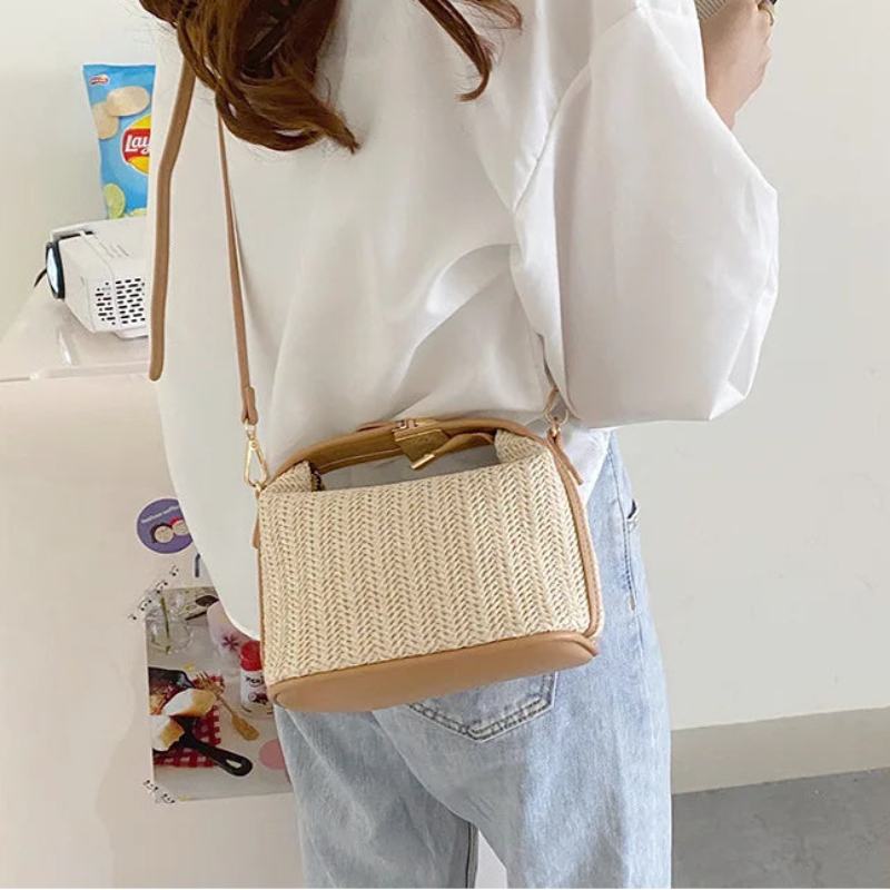 Person wearing a white shirt and light blue jeans with a woven beige handbag.
