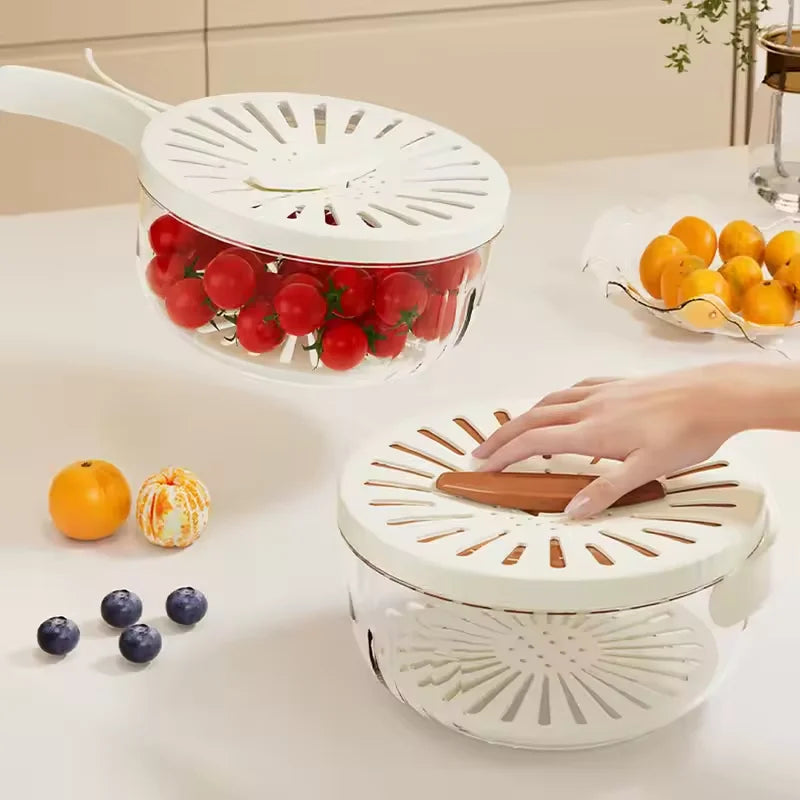 White kitchen strainer with tomatoes on a white surface, surrounded by fruits.