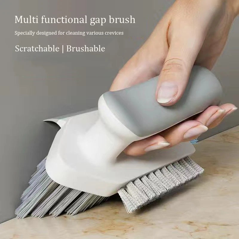 Hand holding a gray and white cleaning brush on a wooden surface with a neutral background