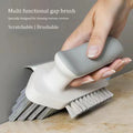 Hand holding a gray and white cleaning brush on a wooden surface with a neutral background