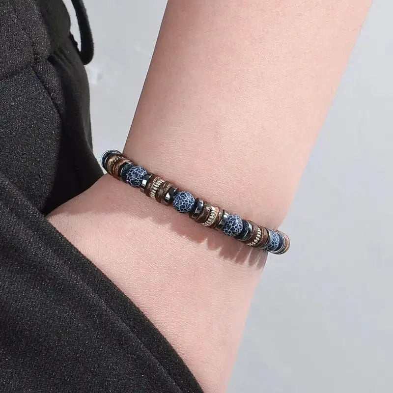 Bracelet with blue and brown beads on a wrist against a neutral background