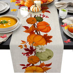Table setting with a decorative table runner featuring pumpkins and leaves on a table with soup and candles.