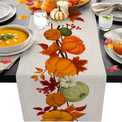 Table setting with a decorative table runner featuring pumpkins and leaves on a table with soup and candles.