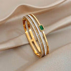 Gold bracelet with emerald stone on beige fabric