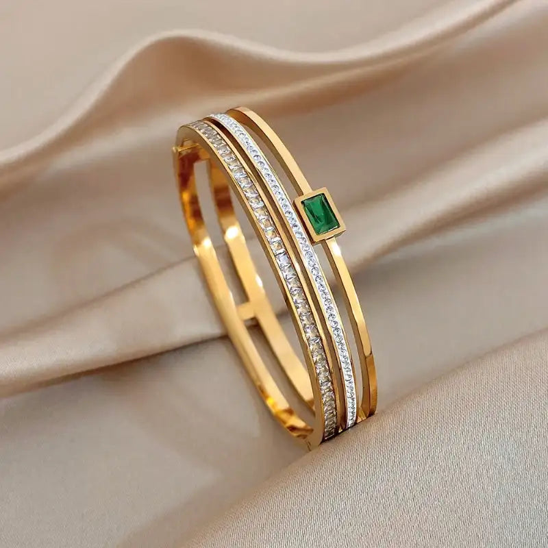 Gold bracelet with emerald stone on beige fabric