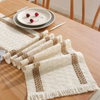 Set of woven placemats on a wooden table with a plate of cherries.