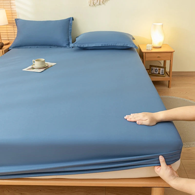 Person adjusting a blue fitted sheet on a bed in a bedroom setting.