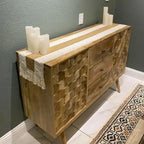 Wooden sideboard with decorative candles against a gray wall
