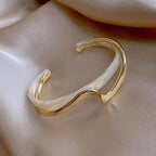 Gold and white cuff bracelet on a beige surface