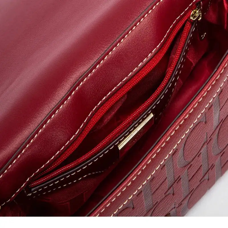 Close-up of a red leather handbag with visible stitching and brand logo.