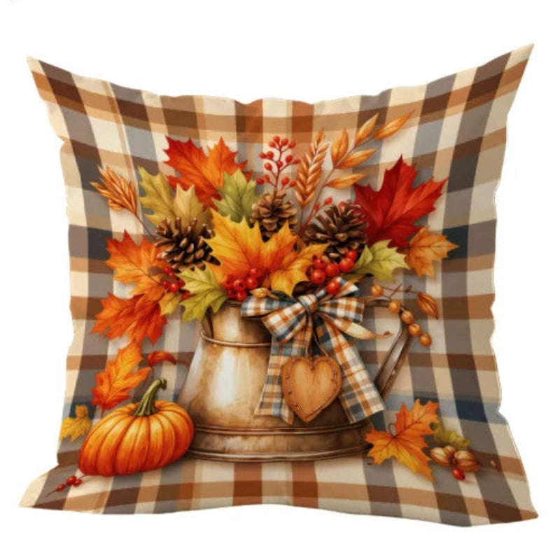 A square throw pillow with a rustic autumn design, featuring a brown and beige plaid border, a central illustration of an autumn bouquet in a metal pitcher, and a small orange pumpkin at the bottom left. Text at the top reads 'a 2D flat print.