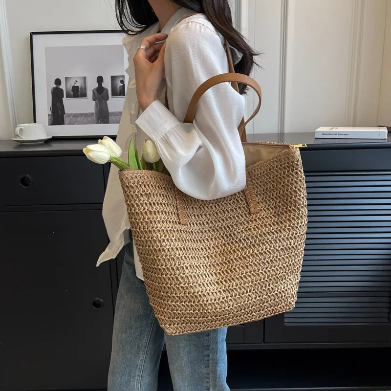 Person holding a woven tote bag with flowers, standing in front of a black cabinet.