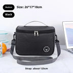 Black insulated lunch bag with gray strap on a white surface with a laptop and oranges.