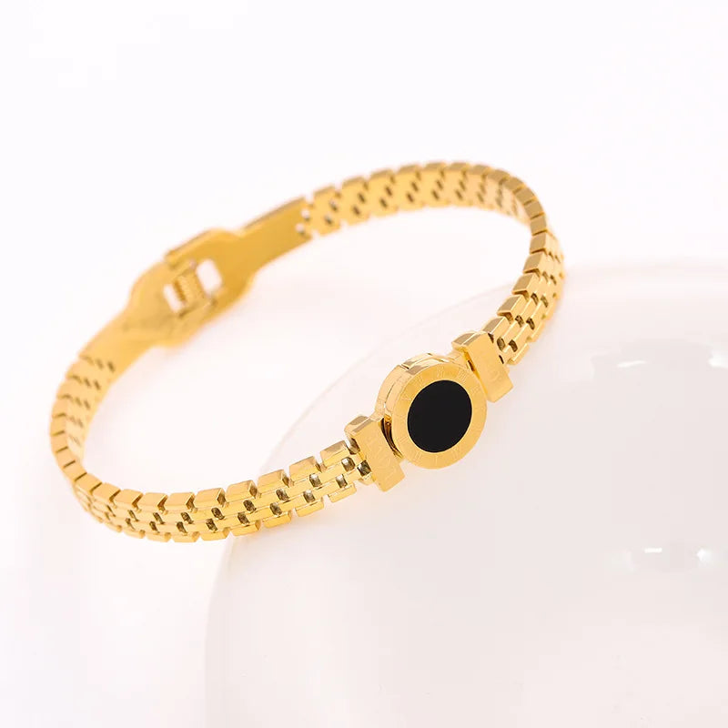 Gold bracelet with a black stone on a white background