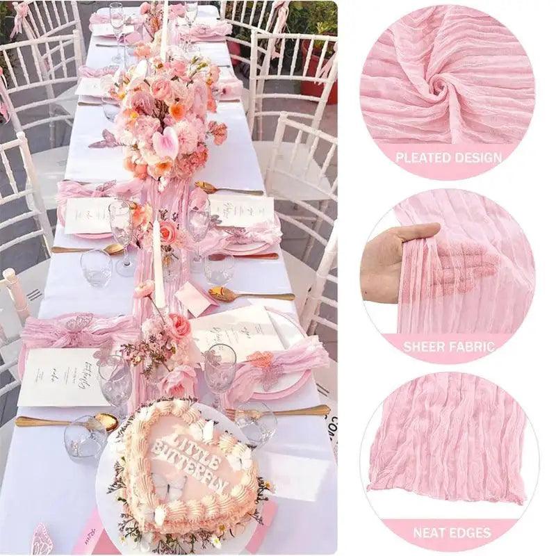 Decorative table setting with pink table runner, flowers, and cake on a white tablecloth.