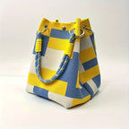 Yellow, blue, and white striped handbag on a light background