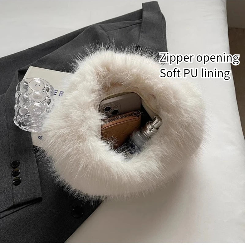 A white faux fur zippered pouch with a soft PU lining, shown holding a phone, wallet, and perfume bottle. The pouch is styled on top of a dark gray blazer and a white surface, with text overlay reading 'Zipper opening Soft PU lining'.